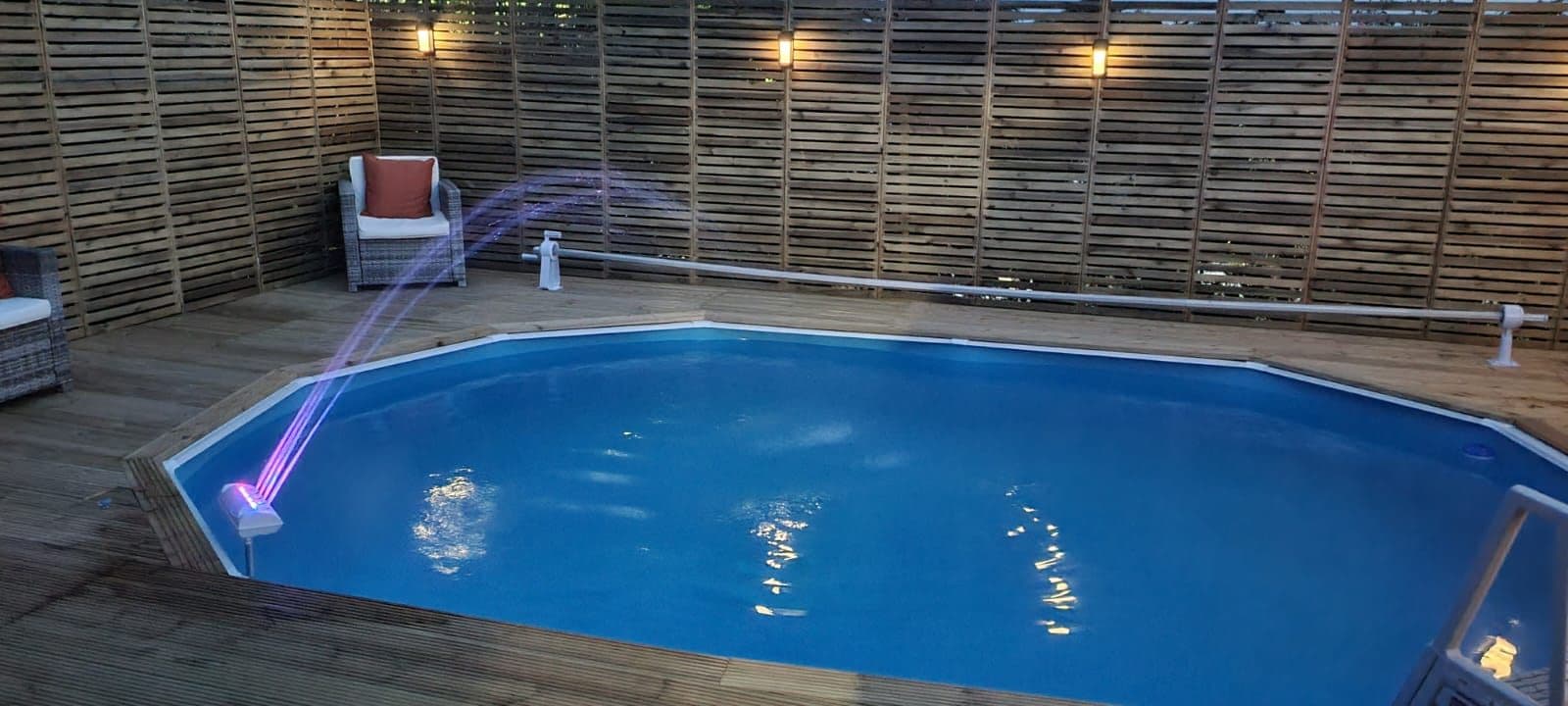 Landscaped garden with lit outdoor pool at dusk