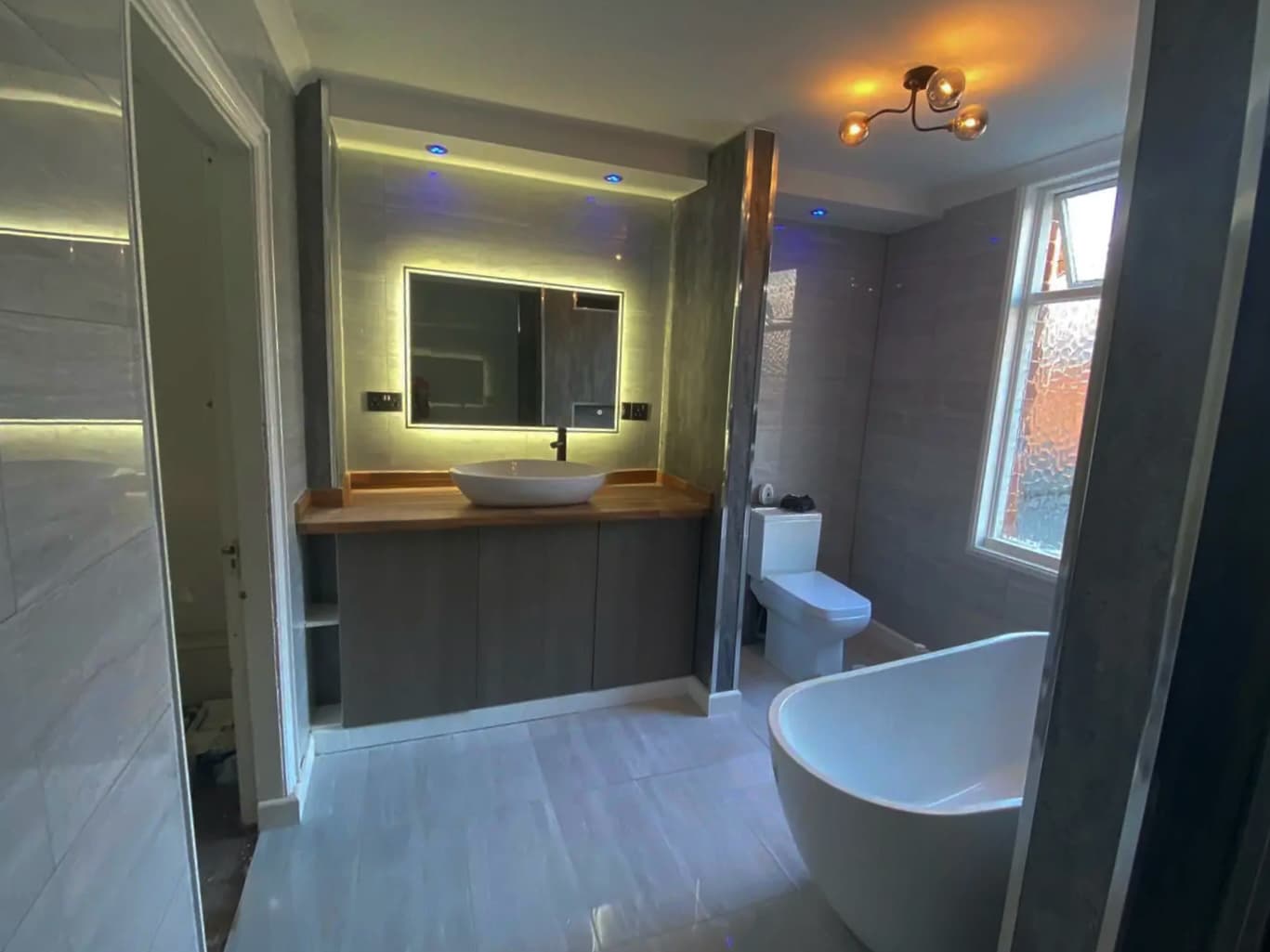 Luxury bathroom with freestanding bath, backlit mirror and vessel sink