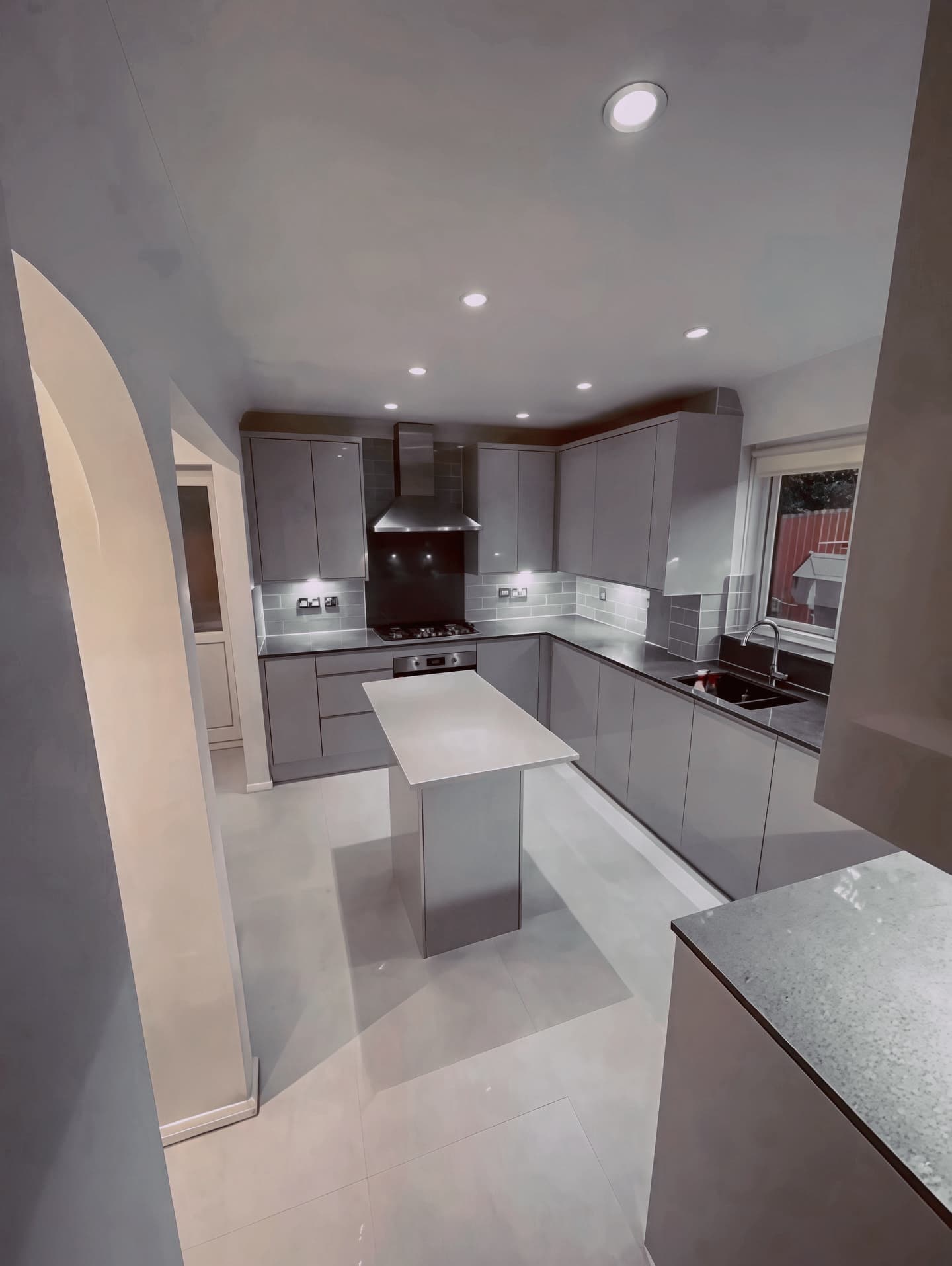 Grey handleless kitchen with central island and gas hob
