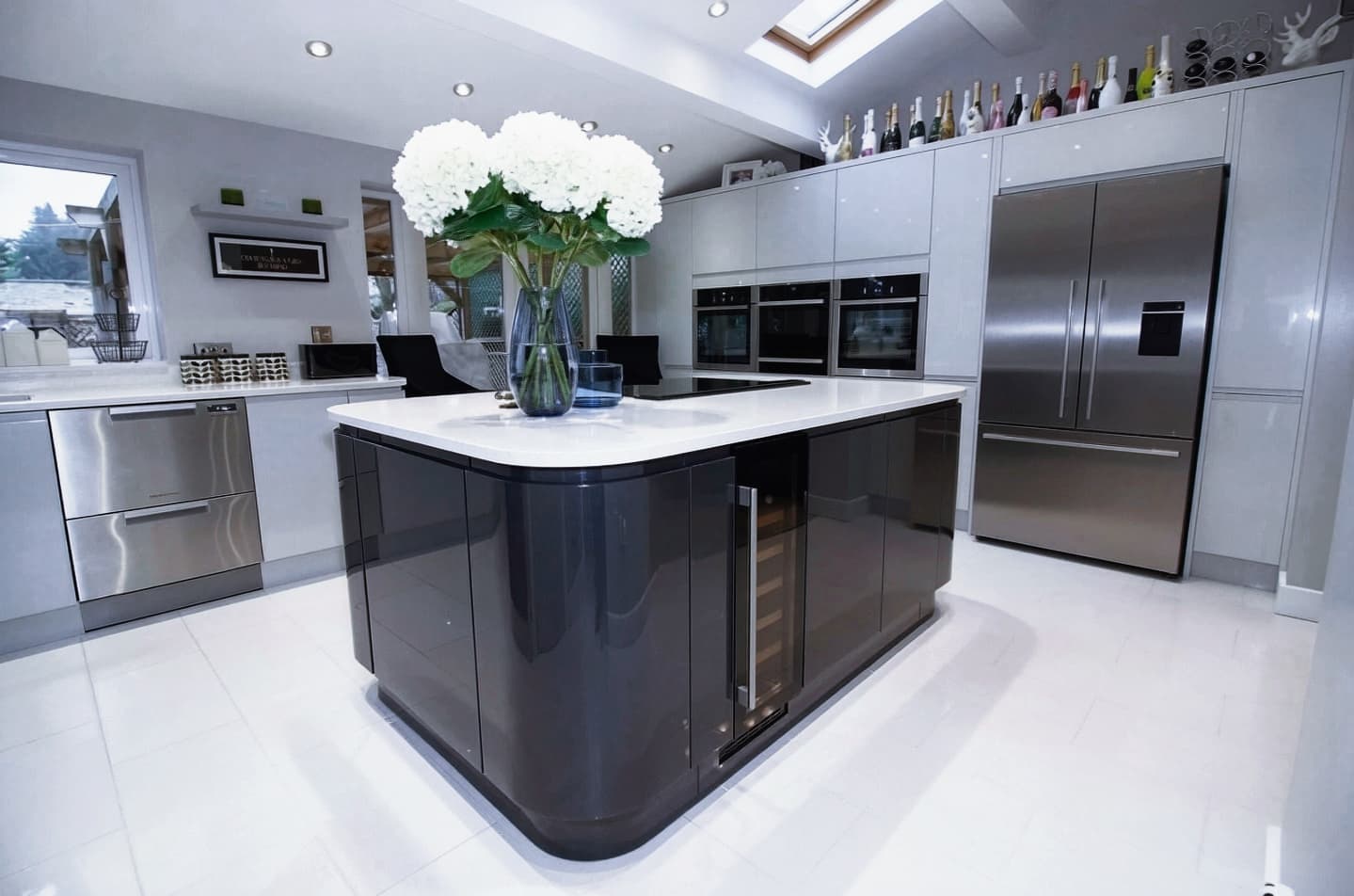 High-gloss black kitchen island with wine cooler beneath a skylight